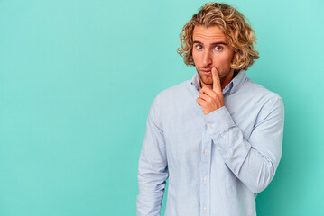 Young caucasian man isolated on blue background looking sideways with doubtful and skeptical expression.