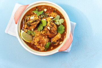 Chicken stewed with tomatoes and vegetables on blue,top view
