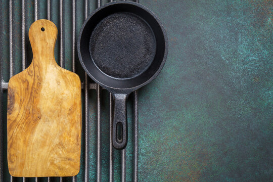 Food background with cast iron pan and cutting board on grill grate with copy space