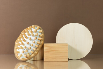 Wooden massage brush on a brown background with wooden scenes for the presentation of your product. Zero waste, eco friendly bathroom and spa accessories.