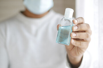 Fototapeta premium young man in face mask holding sanitizer liquid 