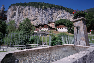 Fototapeta na wymiar Drinking fountain. A water source in mountains village. Alps, Switzerland.