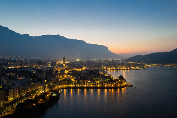 Lecco city on Lake Como aerial shot at sunrise with city lights. - obrazy, fototapety, plakaty