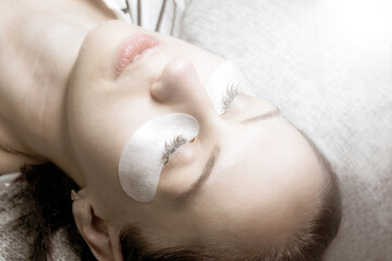 Beautician applies paint to eyelashes, beauty treatment, face view from above