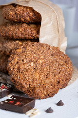 Homemade oatmeal cookies with chocolate and nuts tied with jute thread on baking paper and white wooden background