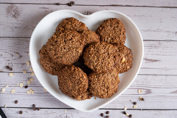 Homemade oatmeal cookies with chocolate and nuts on a plate in the shape of a heart on