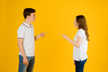 young happy couple man and woman in white t-shirts smiling and laughing on a yellow background..