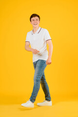 Portrait of a young happy man in white t-shirt smiling and laughing on a yellow background