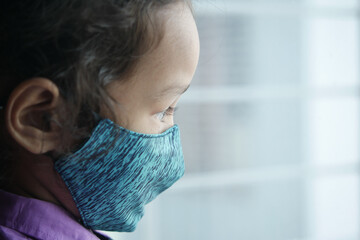 a upset child girl with face mask looking down 