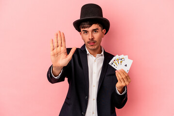 Young caucasian wizard man holding a magic cards isolated on white background standing with outstretched hand showing stop sign, preventing you.