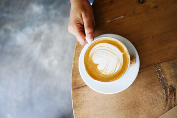 top view of a cup of late coffee with heart shape design on top on cafe table 