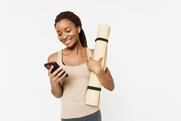 Young black woman using cellphone while posing with fitness mat
