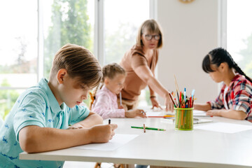 Obraz na płótnie Canvas Mature teacher talking with her pupils during class in art school