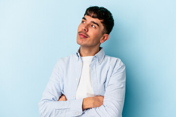 Young mixed race man isolated on blue background dreaming of achieving goals and purposes