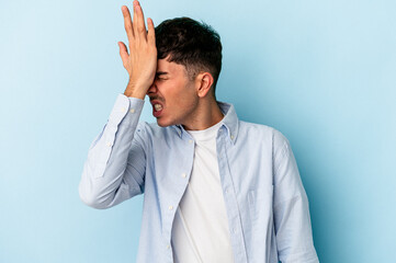 Young mixed race man isolated on blue background forgetting something, slapping forehead with palm...