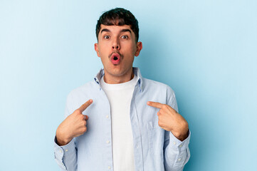 Young mixed race man isolated on blue background pointing upside with opened mouth.