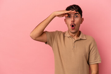 Young mixed race man isolated on pink background looking far away keeping hand on forehead.