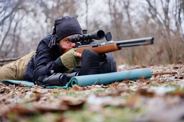 Fototapeta premium Young man aiming at target with the hunting rifle.