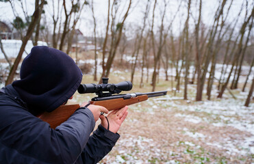 Young man aiming at target with the hunting rifle.