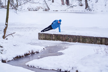 Healthy lifestyle. Young strong man is exercising at snowy park.