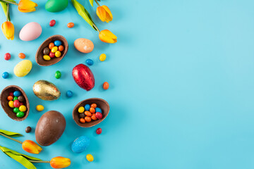 Colorful chocolate Easter eggs on blue bckground. Top view. Copy space	