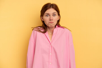 Fototapeta premium Young English woman isolated on yellow background shrugs shoulders and open eyes confused.