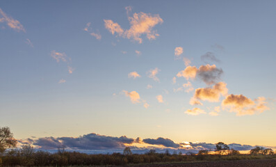 Obraz premium Blue sky with curly clouds and sun, sunset with sun rays.