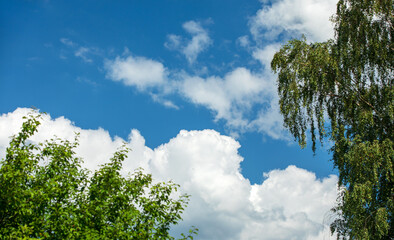 Blue sky with curly clouds and sun, sunset with sun rays.