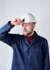 Building contractor, mechanic or electrician portrait. Serious cute caucasian bearded male supervisor, foreman or architect in uniform adjusting his hard hat. High quality vertical image