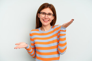 Young English woman isolated on blue background makes scale with arms, feels happy and confident.