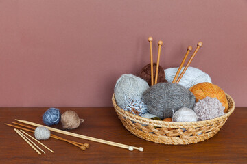 Needlework and DIY concept. Wicker basket with different types of woolen yarn and wooden knitting...