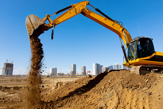 Excavator machine unloading sand or soil at construction site background