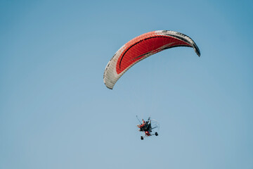 A female tourist is flying with a paramotor pilot in the sky to look at the scenery. Thailand's tourism industry