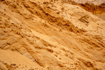 Textural sand, with  relief surface, multi-colored layers and different in size of granules, in outdoor sand career, after mining ore and sand for construction.
