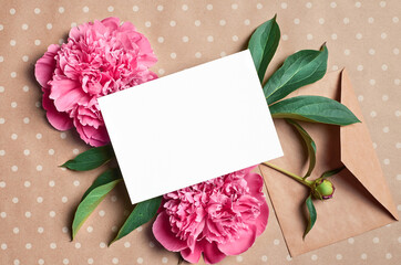 Greeting or invitation card mockup with envelope and pink peony flowers on craft paper background