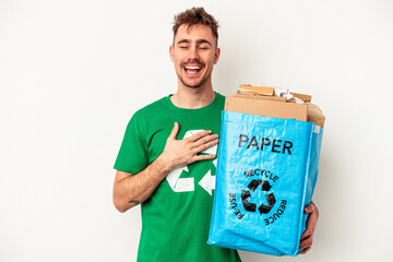 Young caucasian man recycled paper isolated on white background laughs out loudly keeping hand on chest.