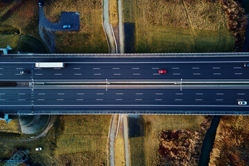 Car traffic moving on highway, aerial view. Countryside road through autumn forest. Road trip, delivery and logistic concept © Lazy_Bear