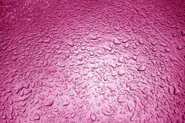 Water drops on metal surface in pink tone.
