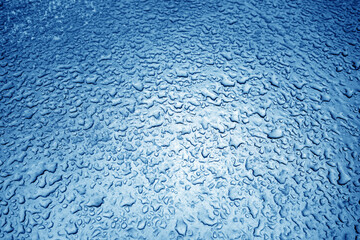 Water drops on metal surface in navy blue tone.