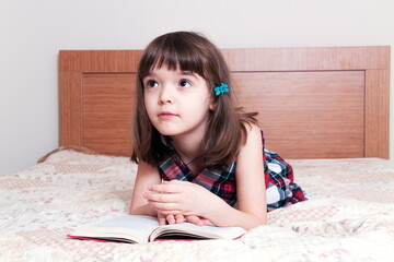 Naklejka premium Little girl reading a book at home