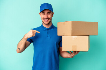 Young delivery caucasian man isolated on blue background person pointing by hand to a shirt copy space, proud and confident