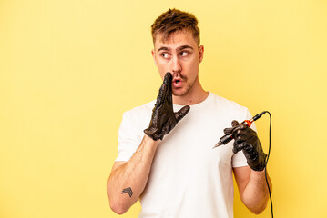 Young caucasian tattoo maker man isolated on yellow background is saying a secret hot braking news and looking aside