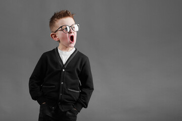 Obraz premium surprised child with an open mouth on gray background. kid in funny glasses.funny grimace little boy
