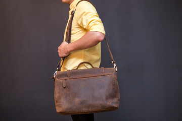 Man with brown leather messenger bag on gray background
