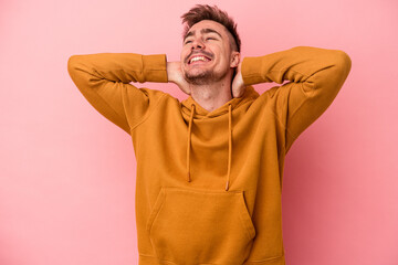 Young caucasian man isolated on pink background feeling confident, with hands behind the head.