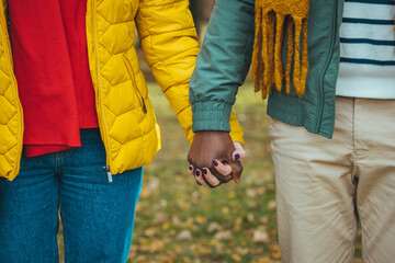 Multiracial couple walking hand in hand .Outdoor shot of young couple in love walking on pathway...
