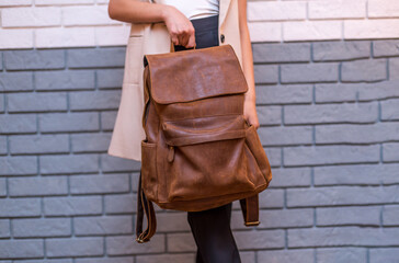 Woman holding brown leather backpack in the hand
