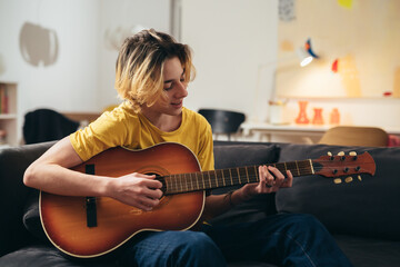 teenage boy playing acoustic guitar at home - Powered by Adobe