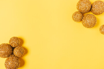 Christmas flat lay frame of golden glitter balls on yellow background