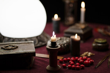 A dark photo of candles, lamps and beads on a fortune teller's table. Interior concept